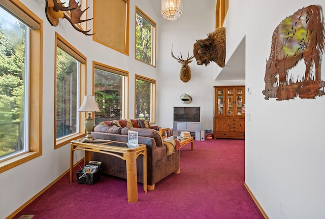 37817 Kings Point Rd, Polson, MT 59860 - carpeted living area with healthy amount of natural light, a towering ceiling, a chandelier, and baseboards
