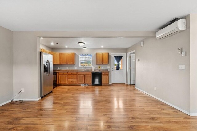 8 Mitchell Way, Columbia Falls, MT 59912 - kitchen with black dishwasher, stainless steel fridge, an AC wall unit, a sink, and light wood finished floors