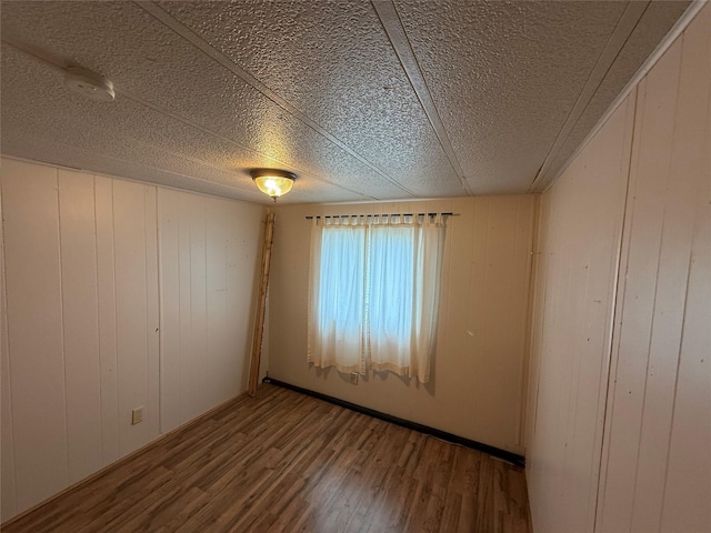 1701 Cooley St Unit 4, Missoula, MT 59802 - spare room featuring wood finished floors, a textured ceiling, and wooden walls