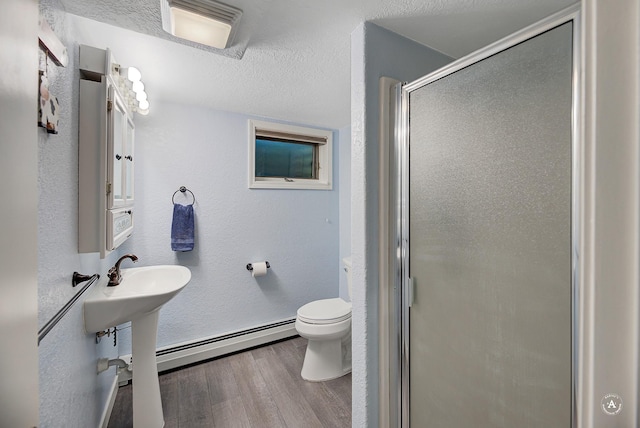 2 N Oregon St, Helena, MT 59601 - bathroom with wood finished floors, a baseboard radiator, a shower stall, toilet, and baseboards