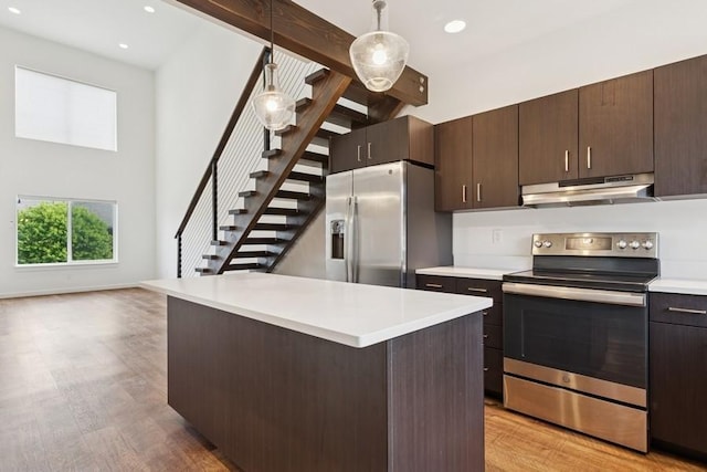 147 Hawthorne Ct Unit B, Whitefish, MT 59937 - kitchen with appliances with stainless steel finishes, under cabinet range hood, light wood-style floors, light countertops, and a high ceiling