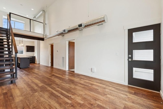 147 Hawthorne Ct Unit B, Whitefish, MT 59937 - unfurnished living room with a towering ceiling, wood finished floors, stairway, and recessed lighting