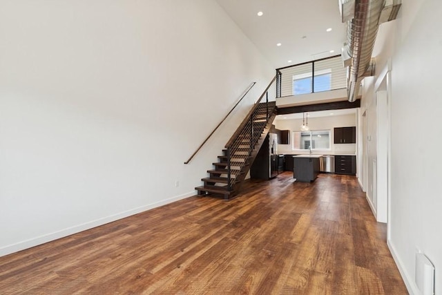147 Hawthorne Ct Unit B, Whitefish, MT 59937 - unfurnished living room featuring stairway, a high ceiling, dark wood-style floors, and recessed lighting