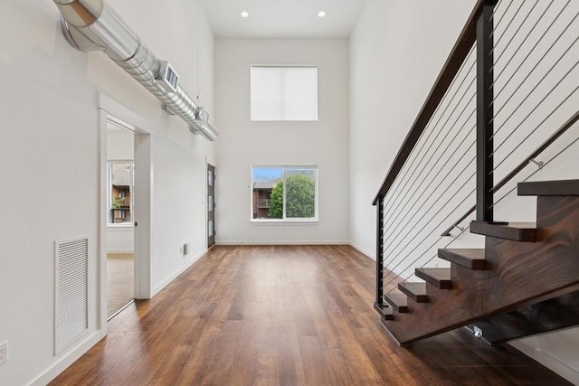 147 Hawthorne Ct Unit B, Whitefish, MT 59937 - unfurnished living room featuring wood finished floors, a high ceiling, stairs, baseboards, and recessed lighting