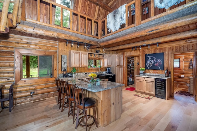 1835 Emmons Canyon Rd, Kila, MT 59920 - kitchen featuring wine cooler, light wood finished floors, track lighting, a peninsula, and log walls