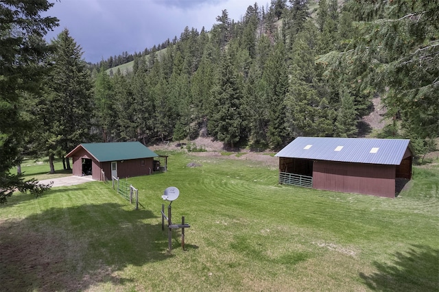 1835 Emmons Canyon Rd, Kila, MT 59920 - view of grassy yard with an outbuilding, a wooded view, an exterior structure, and concrete driveway
