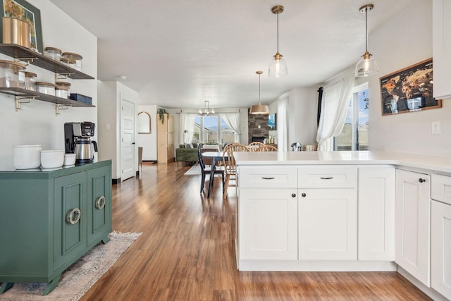 845 Mountain Vista Way, Kalispell, MT 59901 - kitchen with white cabinetry, a peninsula, light wood finished floors, light countertops, and decorative light fixtures