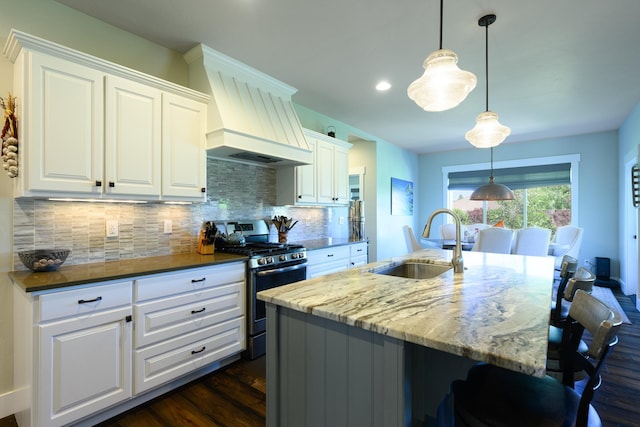 135 E Swift Creek Way, Kalispell, MT 59901 - kitchen featuring stainless steel gas stove, premium range hood, backsplash, dark wood-type flooring, and a kitchen bar