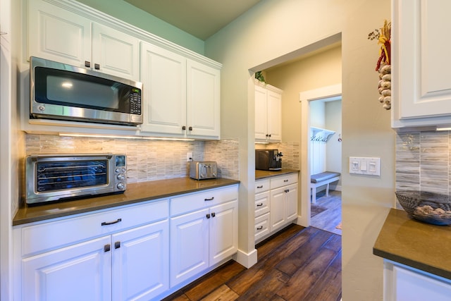 135 E Swift Creek Way, Kalispell, MT 59901 - kitchen with stainless steel microwave, dark countertops, dark wood-style floors, backsplash, and white cabinetry