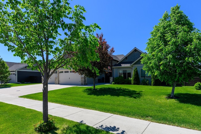 135 E Swift Creek Way, Kalispell, MT 59901 - obstructed view of property featuring concrete driveway, a front yard, stone siding, and a garage