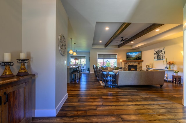 135 E Swift Creek Way, Kalispell, MT 59901 - living area with a ceiling fan, dark wood-type flooring, a fireplace, beam ceiling, and baseboards