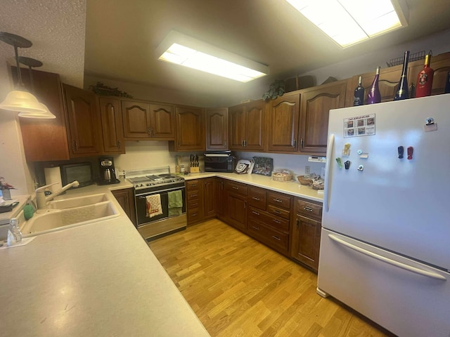 12 Country Club Dr Unit 16, Polson, MT 59860 - kitchen with freestanding refrigerator, stainless steel range oven, light countertops, light wood-style flooring, and a sink