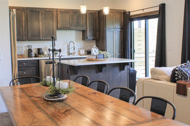 220 Columbia Meadows Dr, Columbia Falls, MT 59912 - kitchen with dark brown cabinets, pendant lighting, a kitchen bar, a sink, and a center island