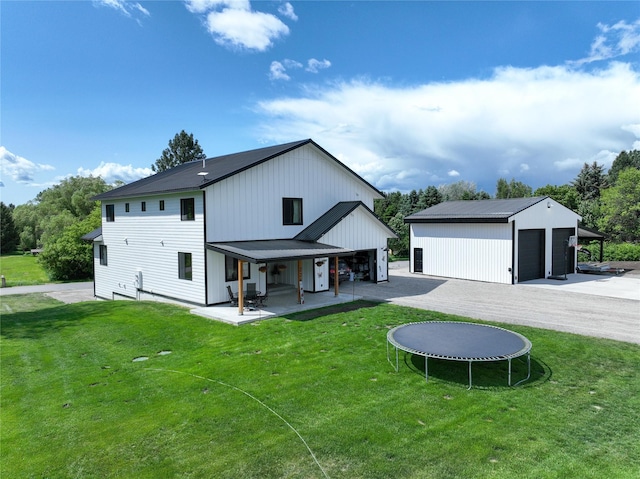 224 Columbia Meadows Dr, Columbia Falls, MT 59912 - back of house featuring a trampoline, a garage, a lawn, and a patio area