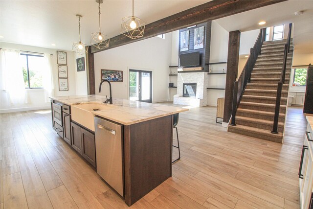224 Columbia Meadows Dr, Columbia Falls, MT 59912 - kitchen with stainless steel dishwasher, a sink, open floor plan, a stone fireplace, and light wood-style floors