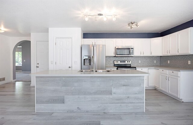 2322 Mary Jane Blvd, Missoula, MT 59808 - kitchen featuring stainless steel appliances, a sink, arched walkways, tasteful backsplash, and an island with sink