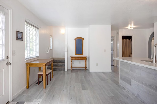 2322 Mary Jane Blvd, Missoula, MT 59808 - unfurnished living room featuring light wood-type flooring, stairs, arched walkways, baseboards, and a sink