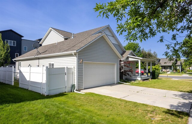 2322 Mary Jane Blvd, Missoula, MT 59808 - view of side of home featuring a garage, concrete driveway, roof with shingles, and a porch