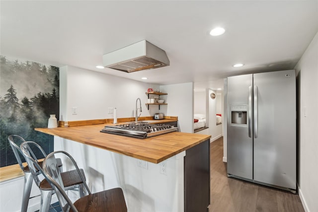 322 Wood Run Dr Unit B, Whitefish, MT 59937 - kitchen featuring appliances with stainless steel finishes, butcher block counters, custom exhaust hood, recessed lighting, and wood finished floors