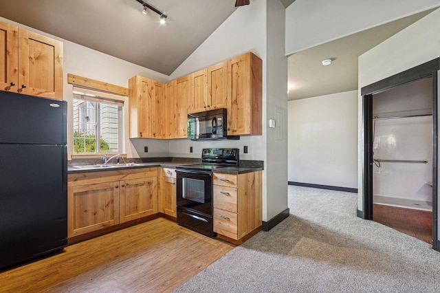 119 5th Ave W, Kalispell, MT 59901 - kitchen with black appliances, a sink, dark countertops, vaulted ceiling, and light brown cabinets
