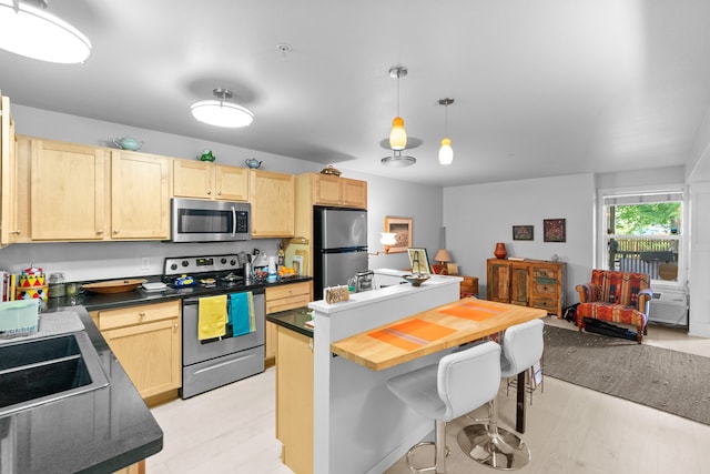 801 N Orange St Unit 108, Missoula, MT 59802 - kitchen featuring stainless steel appliances, light brown cabinetry, dark countertops, and a breakfast bar area