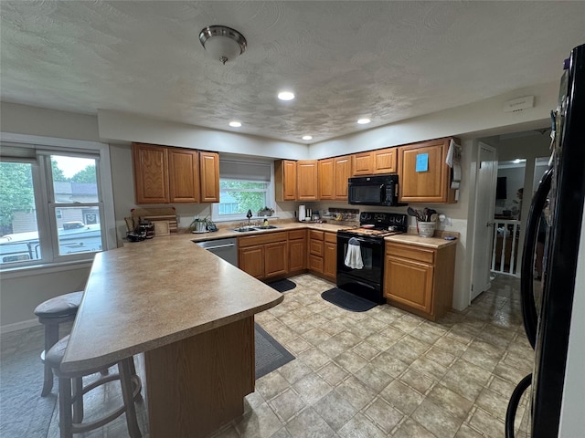 1631 Juniper Dr, Havre, MT 59501 - kitchen with black appliances, a peninsula, a sink, light countertops, and a breakfast bar