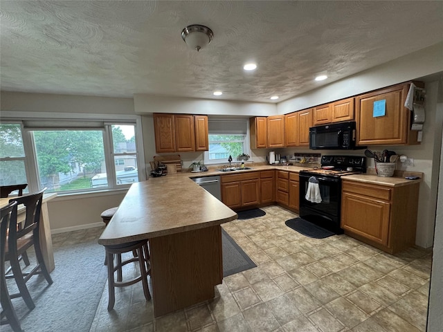 1631 Juniper Dr, Havre, MT 59501 - kitchen featuring black appliances, a peninsula, a sink, a breakfast bar, and brown cabinets