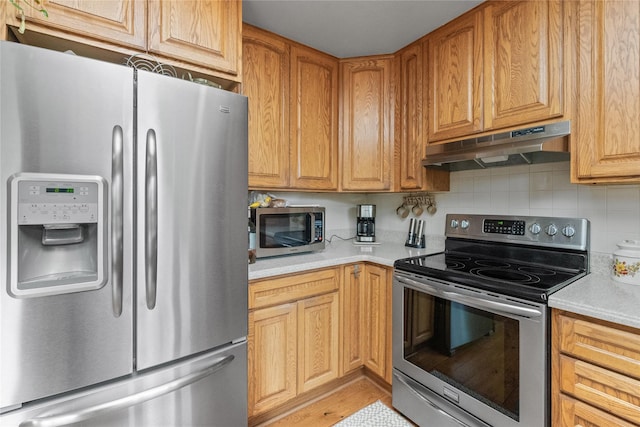 417 56th St S, Great Falls, MT 59405 - kitchen with appliances with stainless steel finishes, under cabinet range hood, light countertops, and decorative backsplash