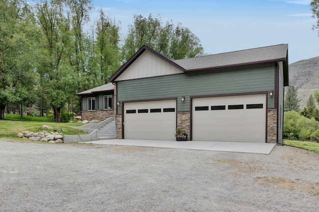 12800 Mill Creek Rd, Lolo, MT 59847 - view of front facade with driveway, stone siding, an attached garage, and board and batten siding