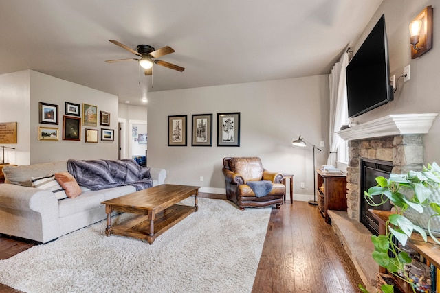 12800 Mill Creek Rd, Lolo, MT 59847 - living area with a ceiling fan, hardwood / wood-style floors, a stone fireplace, and baseboards