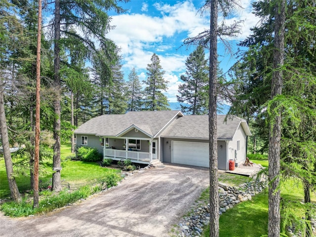 4357 Trumble Creek Rd, Columbia Falls, MT 59912 - ranch-style home featuring a porch, an attached garage, driveway, a front yard, and a shingled roof