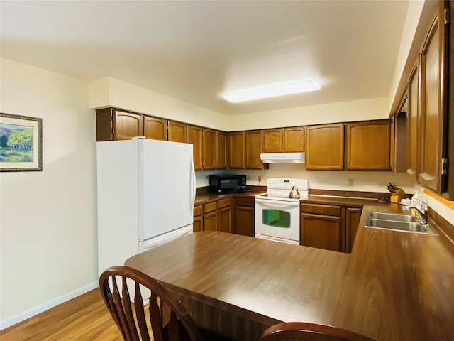 1655 Sunflower Dr, Missoula, MT 59802 - kitchen featuring white appliances, under cabinet range hood, a peninsula, baseboards, and a sink