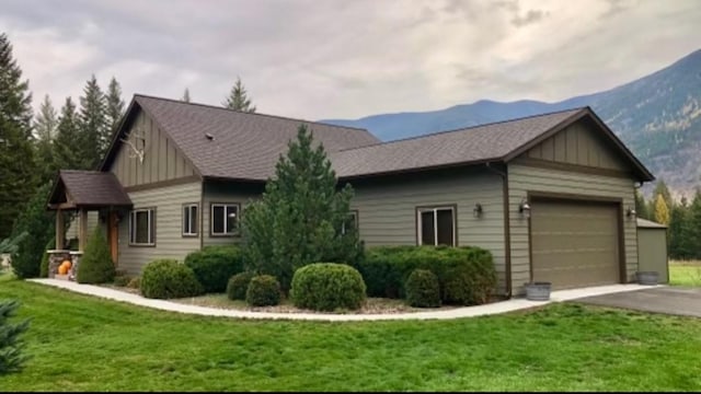 227 Mountain Timbers Dr, Columbia Falls, MT 59912 - view of front of property featuring board and batten siding, driveway, an attached garage, and a front lawn