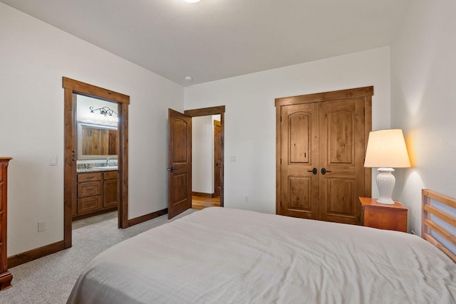74 Wood Ridge Dr, Columbia Falls, MT 59912 - bedroom featuring a sink, baseboards, light carpet, and ensuite bathroom