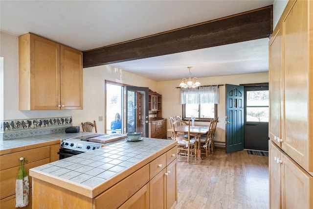 965 Ranch Ln, Kalispell, MT 59901 - kitchen featuring tile countertops, light wood-type flooring, range, a chandelier, and beamed ceiling