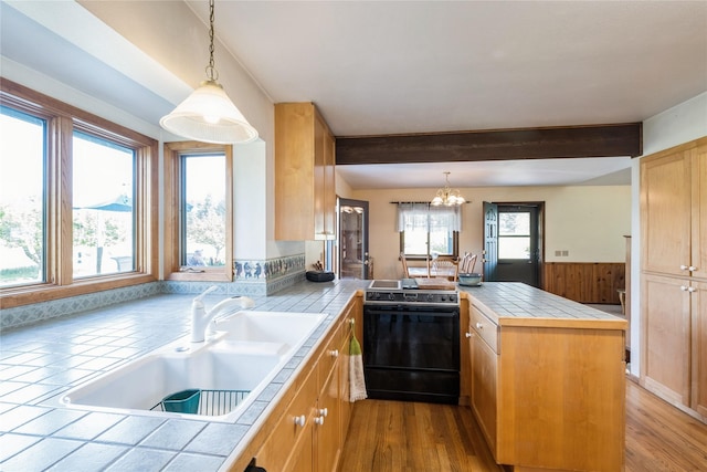 965 Ranch Ln, Kalispell, MT 59901 - kitchen with black range with electric stovetop, tile countertops, a peninsula, a chandelier, and beamed ceiling