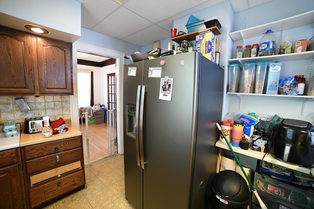 712 9th St N, Great Falls, MT 59401 - kitchen with stainless steel fridge, tasteful backsplash, a drop ceiling, light countertops, and open shelves