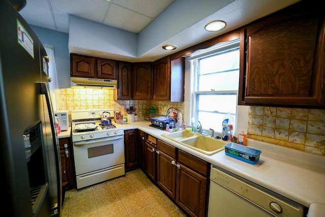 712 9th St N, Great Falls, MT 59401 - kitchen with white gas range, stainless steel refrigerator with ice dispenser, under cabinet range hood, dishwasher, and a sink