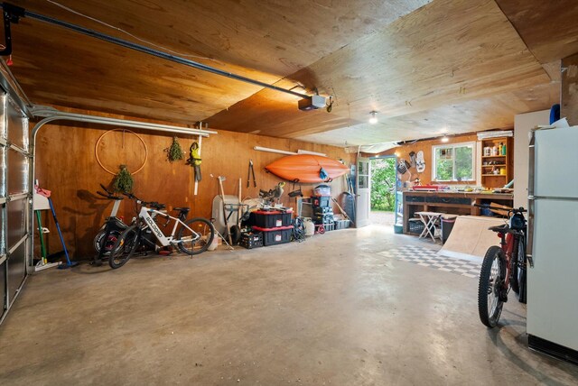 1108 4th Ave W, Columbia Falls, MT 59912 - garage featuring a workshop area, freestanding refrigerator, a garage door opener, and wood walls