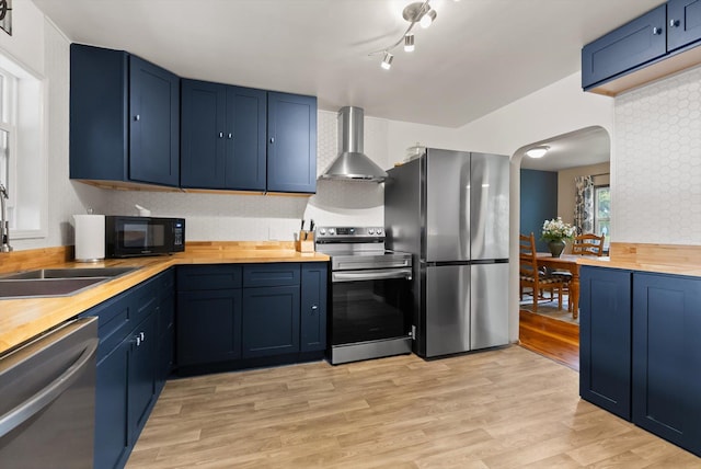 1108 4th Ave W, Columbia Falls, MT 59912 - kitchen with stainless steel appliances, wall chimney exhaust hood, blue cabinets, butcher block counters, and arched walkways