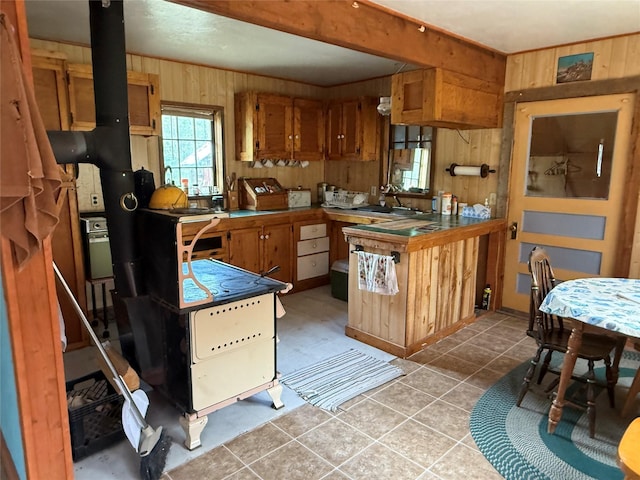 63450 US Highway 2, Libby, MT 59923 - kitchen featuring wood walls, brown cabinetry, light tile patterned flooring, and a wood stove
