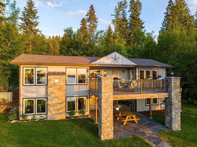 34777 Compass Ln, Polson, MT 59860 - back of property featuring a yard, a patio area, stone siding, board and batten siding, and roof with shingles