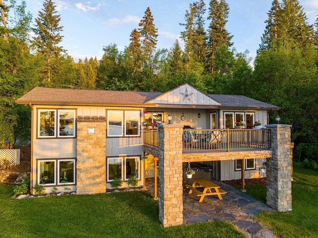 34777 Compass Ln, Polson, MT 59860 - back of house featuring a patio, a yard, stone siding, board and batten siding, and a shingled roof