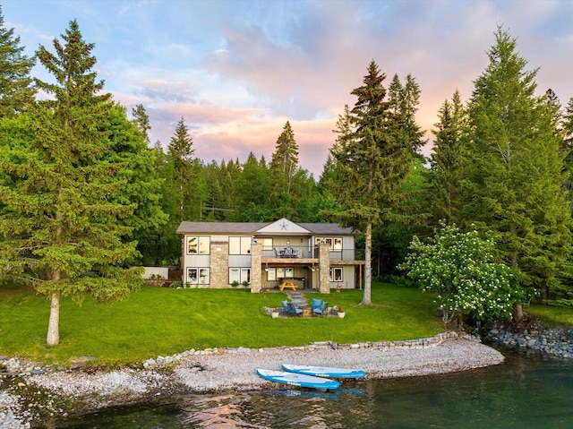 34777 Compass Ln, Polson, MT 59860 - rear view of house featuring a yard, a water view, a patio area, and a wooded view