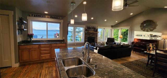 34777 Compass Ln, Polson, MT 59860 - kitchen with a sink, wood finished floors, brown cabinets, vaulted ceiling, and a fireplace