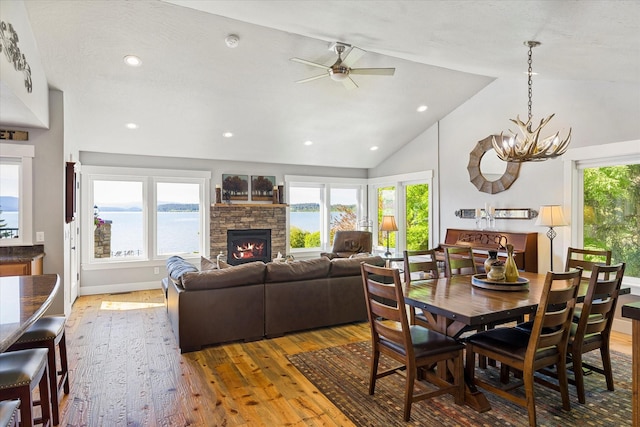 34777 Compass Ln, Polson, MT 59860 - dining area featuring wood-type flooring, a fireplace, vaulted ceiling, a ceiling fan, and a chandelier