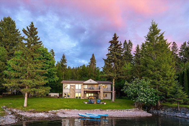 34777 Compass Ln, Polson, MT 59860 - back of property at dusk featuring a yard and a deck with water view