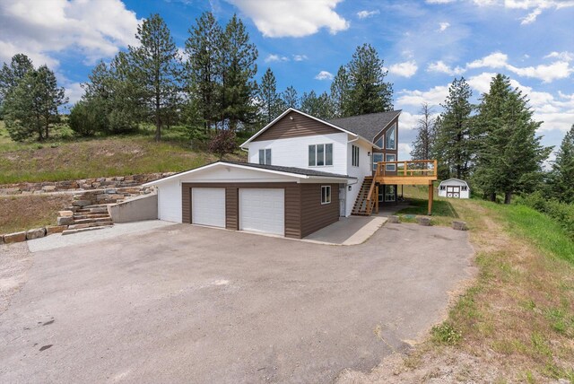35280 Bennington Ln, Polson, MT 59860 - view of side of property featuring stairs, a wooden deck, a garage, and an outdoor structure