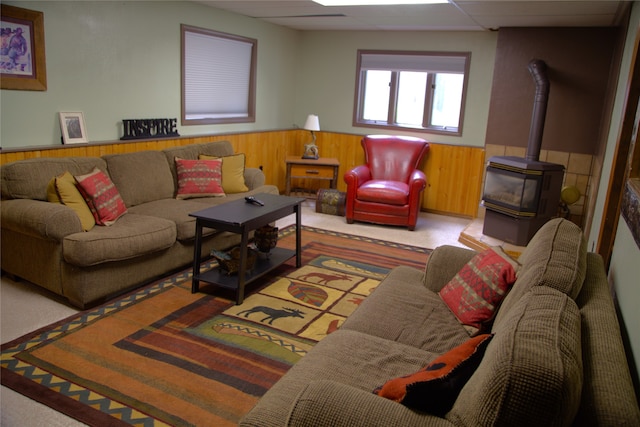 189 Dawn Dr, Columbia Falls, MT 59912 - carpeted living room featuring wainscoting, a paneled ceiling, a wood stove, and wooden walls