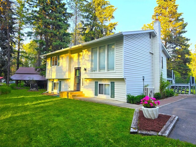 189 Dawn Dr, Columbia Falls, MT 59912 - back of property featuring a chimney, a lawn, and ac unit